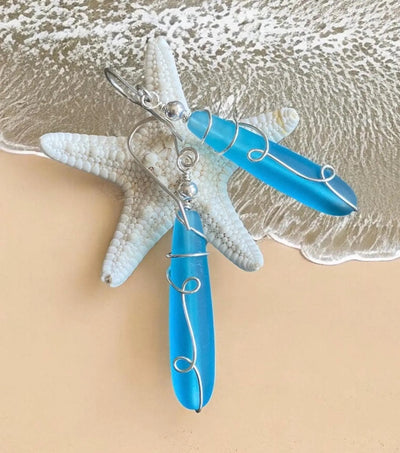 Wire wrapped long sea glass earrings in sterling silver with pacific blue beach glass dangle design